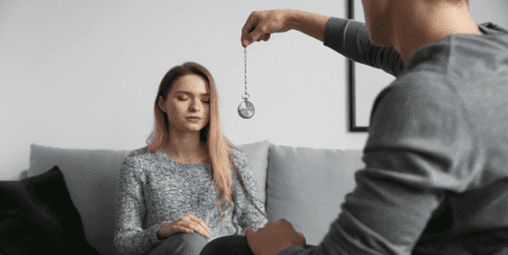 O que é Hipnose: um homem hipnotizando uma mulher com um relógio de bolso usando uma indução de pendulo.